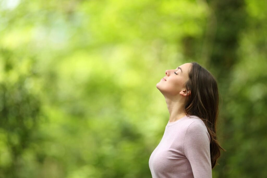 Mujer respirando bien el el bosque