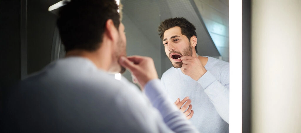 Hombre mirándose al espejo por dolor en sus dientes